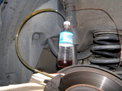 (Image: Brake flush in progress with waste bottle)