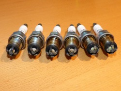 (Image: Closeup of six old spark plugs in a lineup)